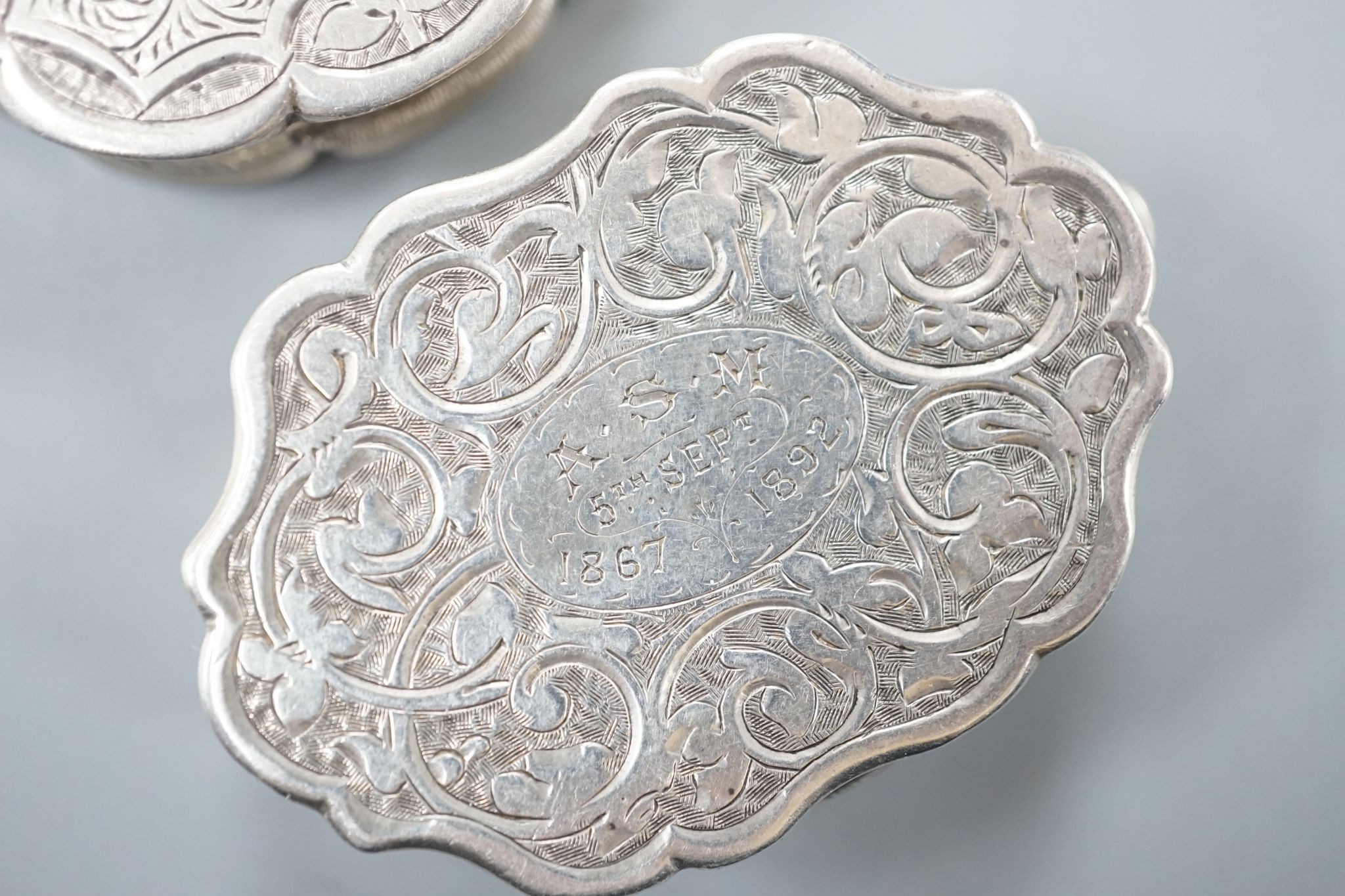 A Victorian engraved silver cusped oval vinaigrette, Hilliard & Thomasson, Birmingham, 1882, 39mm and a larger vinaigrette by George Unite, with engraved inscription.